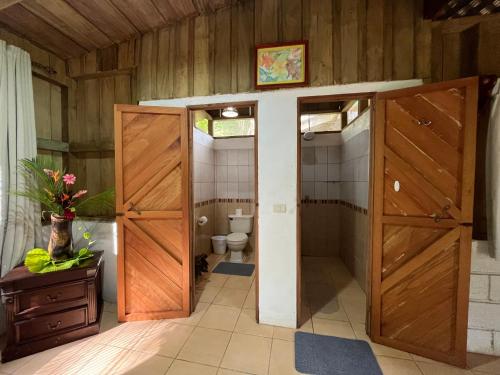 a bathroom with two wooden doors and a toilet at El Zota Hotel in Cariari