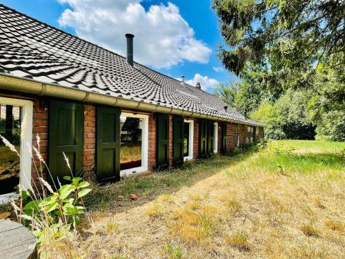an old brick house with green doors and windows at Spacious Farmhouse near Forest in Stramproy in De Horst