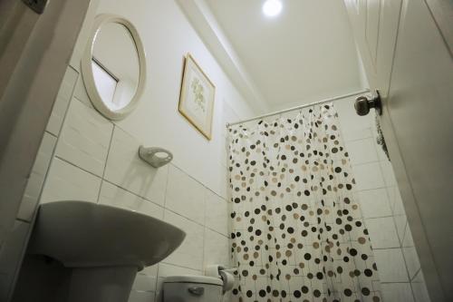 y baño con cortina de ducha y lavamanos. en Hospedaje El Velero, en Paracas
