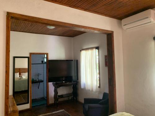 a living room with a television and a mirror at Pousada Sítio Itaúna in Penedo