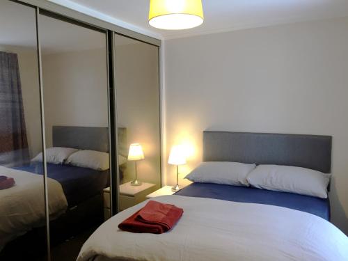 a bedroom with two beds and a mirror at Dunbar Serviced Apartment in Dunbar