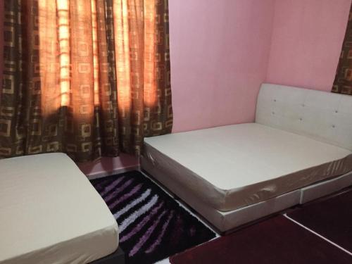 een kamer met 2 bedden en een gordijn bij Guesthouse Adam in Pengkalan Cepa