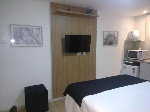 a hotel room with a bed and a microwave at Bauten Cabo Branco 310 in João Pessoa