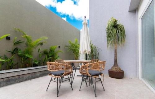 a patio with a table and chairs and a palm tree at Bauten Cabo Branco 310 in João Pessoa