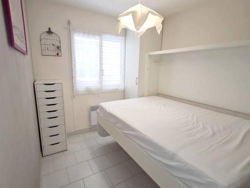 une chambre blanche avec un lit et une fenêtre dans l'établissement Appartement Rénové T3: Parking, Wi-Fi, Piscine, Tennis, à 150 m de la Plage et Commerces - FR-1-316-283, à Six-Fours-les-Plages
