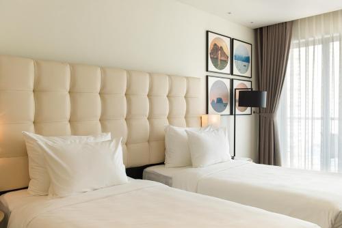 a hotel room with two beds and a large window at Hotel Soleil Ha Long, Trademark Collection by Wyndham in Ha Long