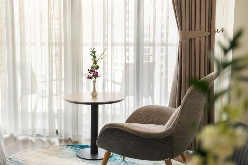 a chair and a table in front of a window at Hotel Soleil Ha Long, Trademark Collection by Wyndham in Ha Long