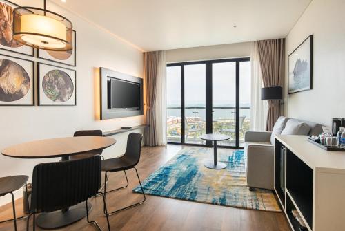 a living room with a table and chairs and a television at Hotel Soleil Ha Long, Trademark Collection by Wyndham in Ha Long