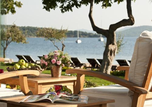 a table with fruit and a book on a table with a lake at Ortunc Hotel - Cunda Island (Adult Only) in Ayvalık