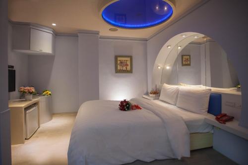 a bedroom with a large white bed with a blue ceiling at Showart Hotel in Taipei