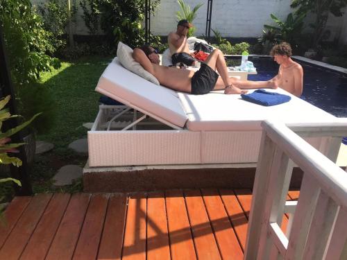 a group of people laying on a bed in a pool at BALI AMED FEEL HOME VILLA in Amed