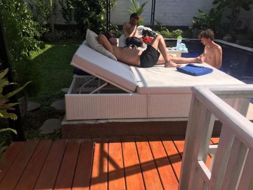 a group of people laying on a bed by a pool at BALI AMED FEEL HOME VILLA in Amed