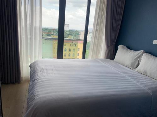 a bed in a room with a large window at Ficus Suites in Hanoi
