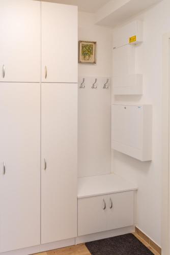 a white kitchen with white cabinets and a shelf at SWEET HOME Apartman , 30sqm studio, free private parking, mountain view, balcony, 20 min from downtown in Budapest