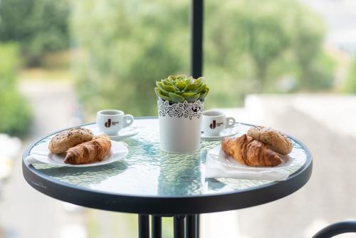 a table with two plates of pastries and cups of coffee at SWEET HOME Apartman , 30sqm studio, free private parking, mountain view, balcony, 20 min from downtown in Budapest
