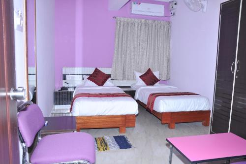 a bedroom with two beds and a table and chairs at Brahma Inn in Bangalore