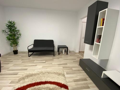 a living room with a black chair and a rug at Grove Apartment in Buzau