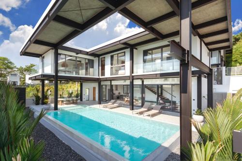 an exterior view of a house with a swimming pool at Loft Style 4BR Villa Sunset Garden 4 with 12m Salt Water Pool, near NaiHarn in Rawai Beach