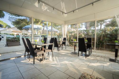 a conservatory with a table and chairs on a patio at Hôtel Le Méditerranée in Hyères
