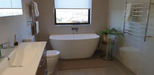a bathroom with a tub and a toilet and a window at A Sweet Escape in Bridport