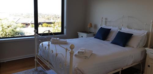 a bedroom with a white bed with blue pillows and a window at A Sweet Escape in Bridport