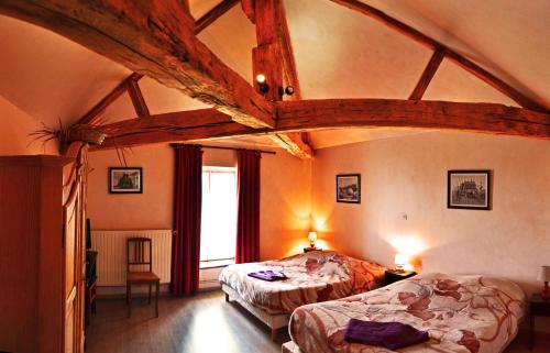 a bedroom with two beds in a room with a wooden ceiling at La Ferme des 3 Suissesses in Saint-Paul