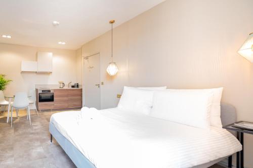 a bedroom with a white bed and a kitchen at The Den Newly Build Apartment 7-Minutes From Rotterdam City Central Station app2 in Schiedam