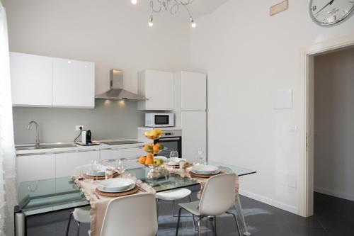 a white kitchen with a glass table and chairs at Artemisia in Viareggio