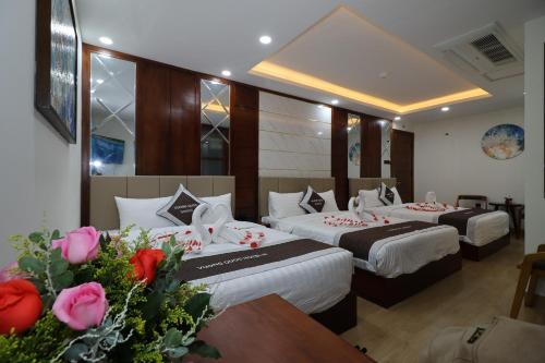 duas camas num quarto de hotel com rosas na mesa em Vương Quốc 3 Hotel em Quy Nhon