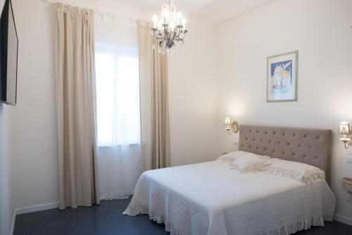 a white bedroom with a bed and a chandelier at Artemisia in Viareggio