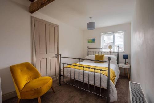 1 dormitorio con 1 cama y 1 silla amarilla en Y Cwtsh, en Llandeilo