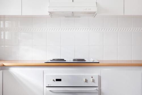 a white tiled kitchen with a stove top oven at Nautica Residences Hillarys in Perth