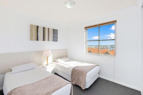 two beds in a white room with a window at Nautica Residences Hillarys in Perth