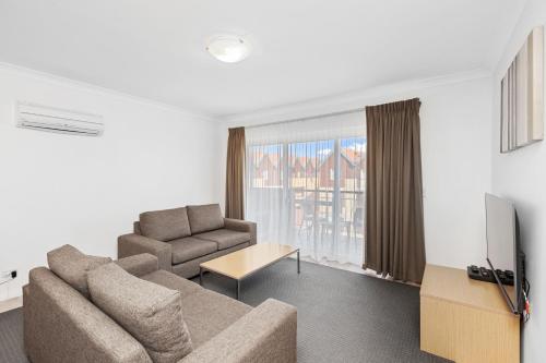 a living room with a couch and a tv at Nautica Residences Hillarys in Perth