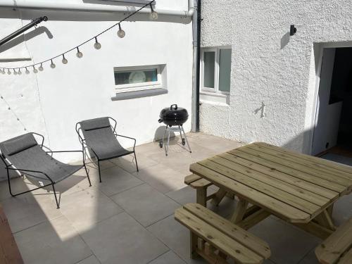 a patio with a wooden picnic table and chairs at Contemporary living with amazing views. Pembrokeshire in Pembrokeshire