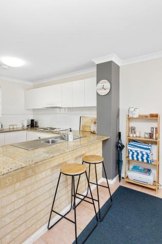 a kitchen with two bar stools and a counter at Nautica Residences Hillarys in Perth