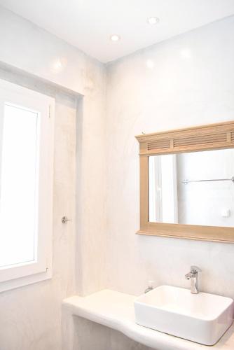 a white bathroom with a sink and a mirror at Tzamaros Studios in Mérikhas