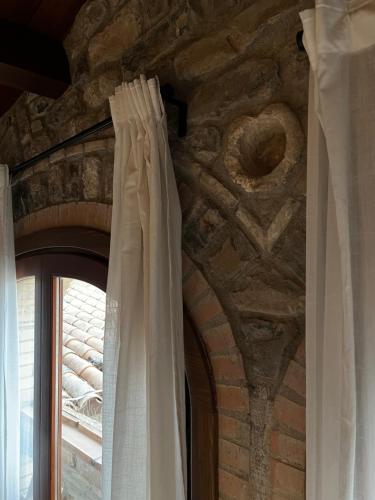a window with white curtains and a stone wall at Ca La Gràcia in Cabrianas