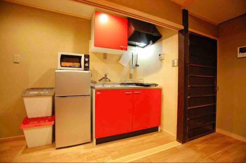 a small kitchen with a refrigerator and a microwave at Nijo Castle, Kinkakuji.etc 西陣・京町家の宿「三石」 in Kyoto