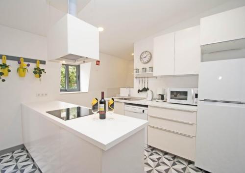 a white kitchen with white cabinets and a sink at In Downtown - Villa Serenity in Albufeira