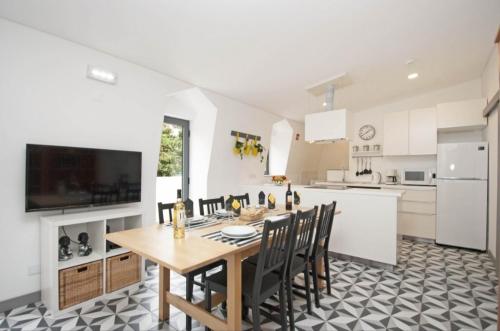 a white kitchen with a wooden table and chairs at In Downtown - Villa Serenity in Albufeira