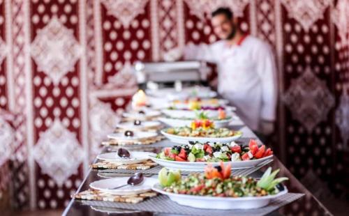 un lungo tavolo con piatti di cibo sopra di Orbit camp a Wadi Rum