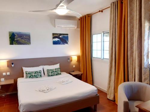 une chambre d'hôtel avec un lit et une chaise dans l'établissement Hôtel Les Embruns Du Baril, à Basse Vallée