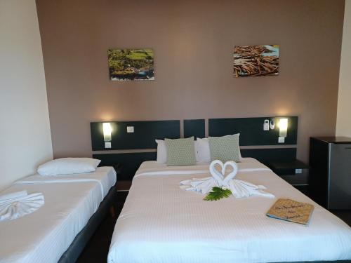 two beds in a hotel room with a bow on them at Hôtel Les Embruns Du Baril in Basse Vallée