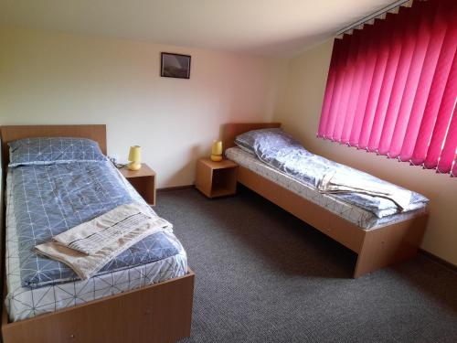 two twin beds in a room with pink curtains at Casa cu flori in Bîrsău