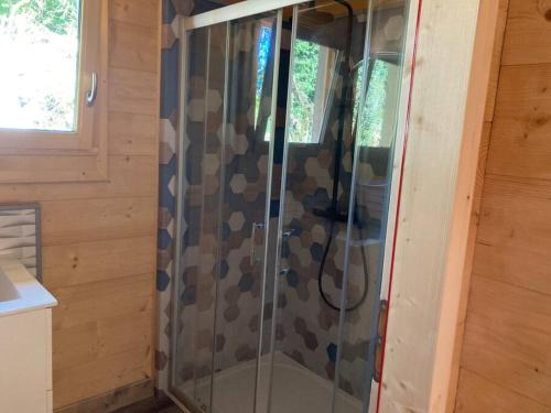 - une douche avec une porte en verre dans la chambre dans l'établissement Forest Jura Lodge - Chalet des sapins, à Alièze