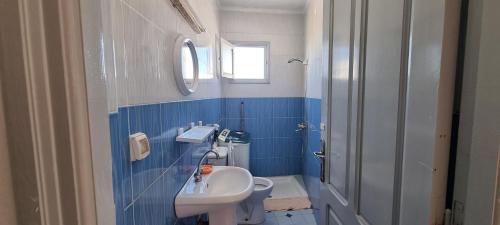 baño azul y blanco con lavabo y aseo en Appartement meublée à Erriadh en Erriadh