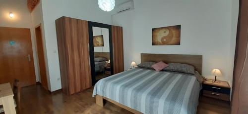 een slaapkamer met een bed met een gestreepte deken en een spiegel bij Apartments ALTO in Rovinj