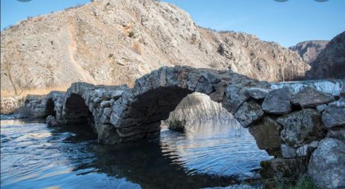 an old stone bridge over a body of water at Apartman Milan in Obrovac