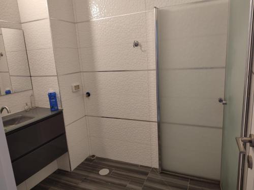 a shower with a glass door next to a sink at Lovely three-room apartment above the promenade in Ashdod